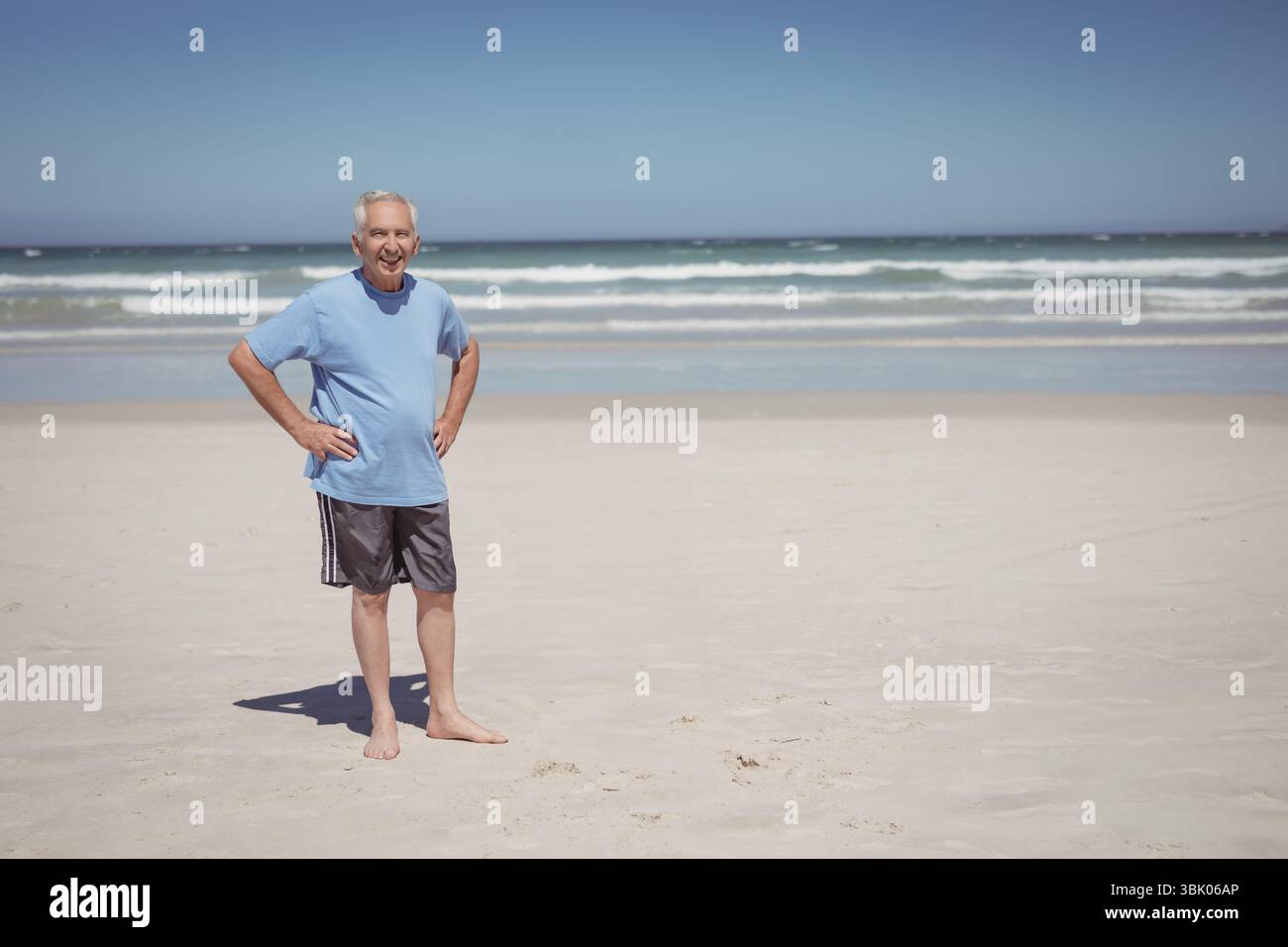 Uomo anziano a piedi nudi su una spiaggia sabbiosa, con dolci onde oceaniche al di sopra della linea dell'orizzonte, copia spazio Foto Stock