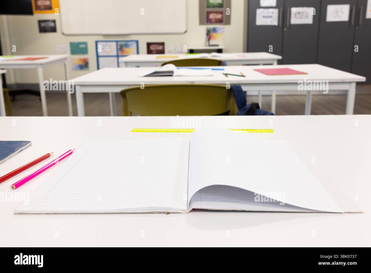 Apri il notebook e le matite sulla scrivania dell'aula, pronti per l'apprendimento scolastico Foto Stock