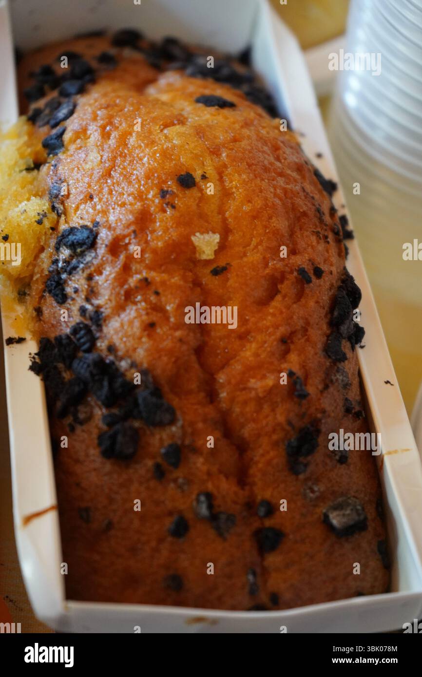 Torta appena sfornata con gocce di cioccolato in una muffa di carta. Crosta marrone dorato, consistenza umida e un'atmosfera fatta in casa, perfetta per la scena dei dessert Foto Stock
