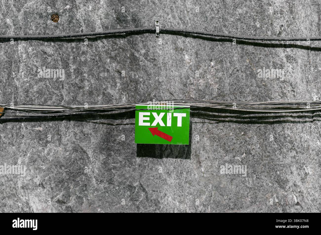 Cartello di uscita verde sulla parete sotterranea della grotta Foto Stock