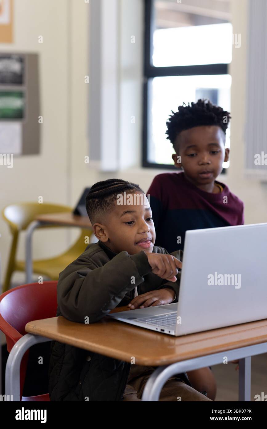 Ragazzi diversi che collaborano al laptop in classe, concentrandosi sul progetto insieme, a scuola Foto Stock