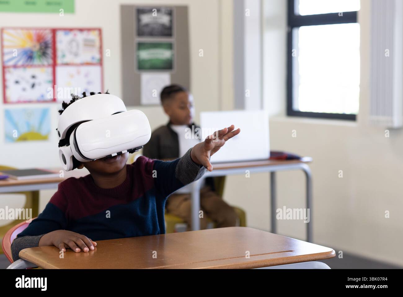 Ragazzo afroamericano che usa il visore vr in classe, esplora il mondo virtuale, a scuola Foto Stock