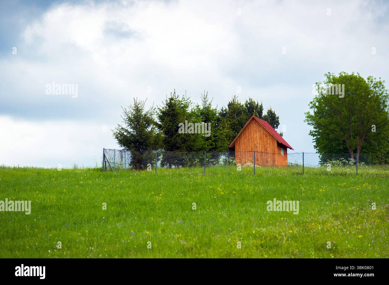Piccola casa in legno sulla cima di una grande collina Foto Stock