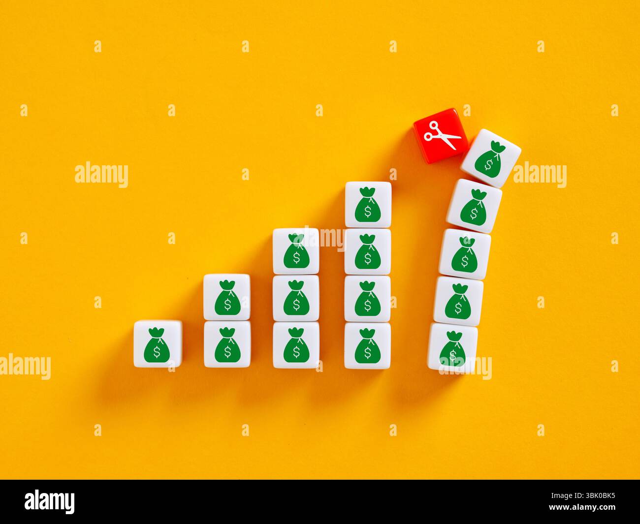 Forbici che tagliano la parte superiore di un grafico crescente di sacchetti di denaro. Recessione economica, inflazione, tagli di bilancio o crisi Foto Stock