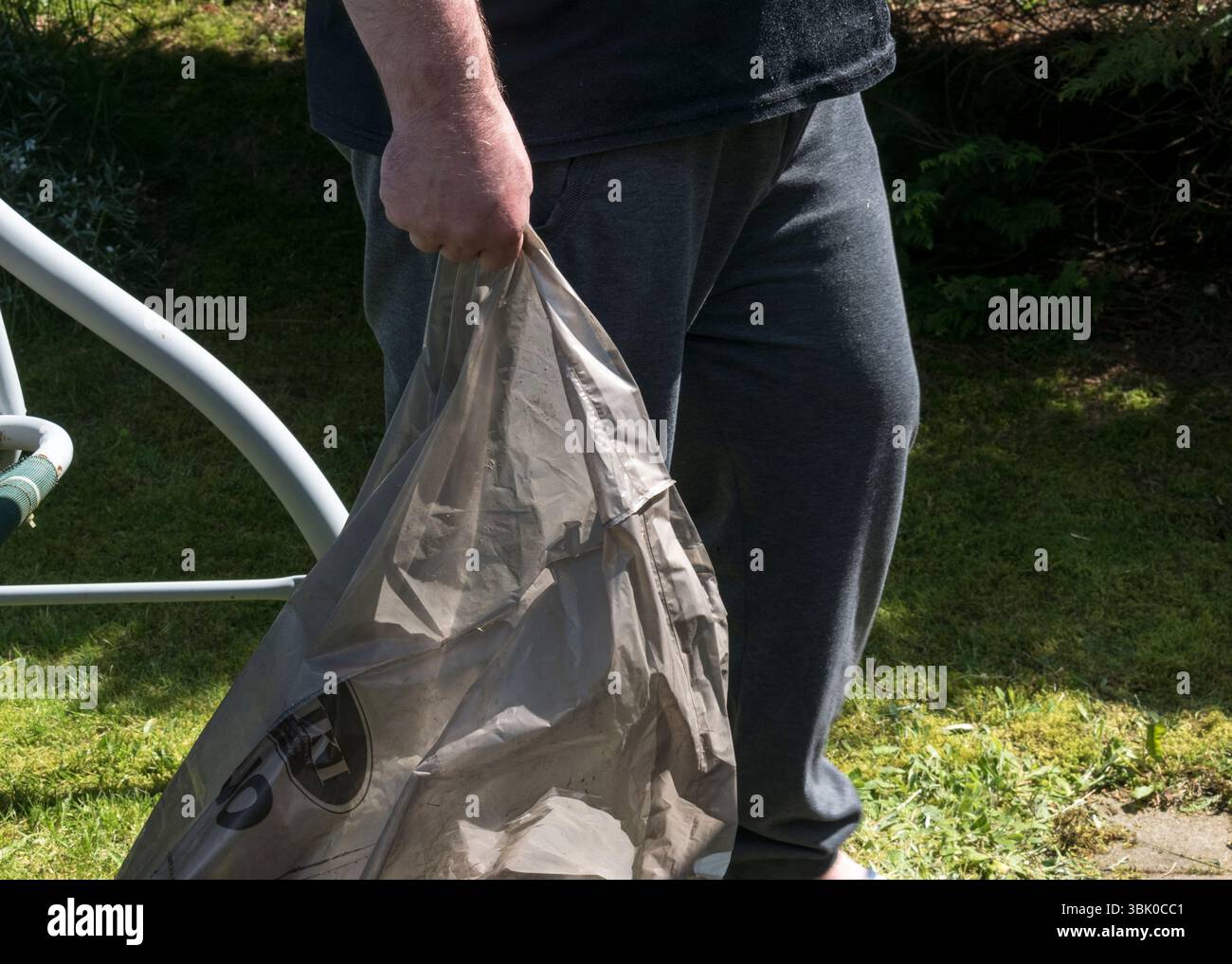 Giardinaggio ecologico - uomo che trasporta un sacco per rifiuti biodegradabili Foto Stock