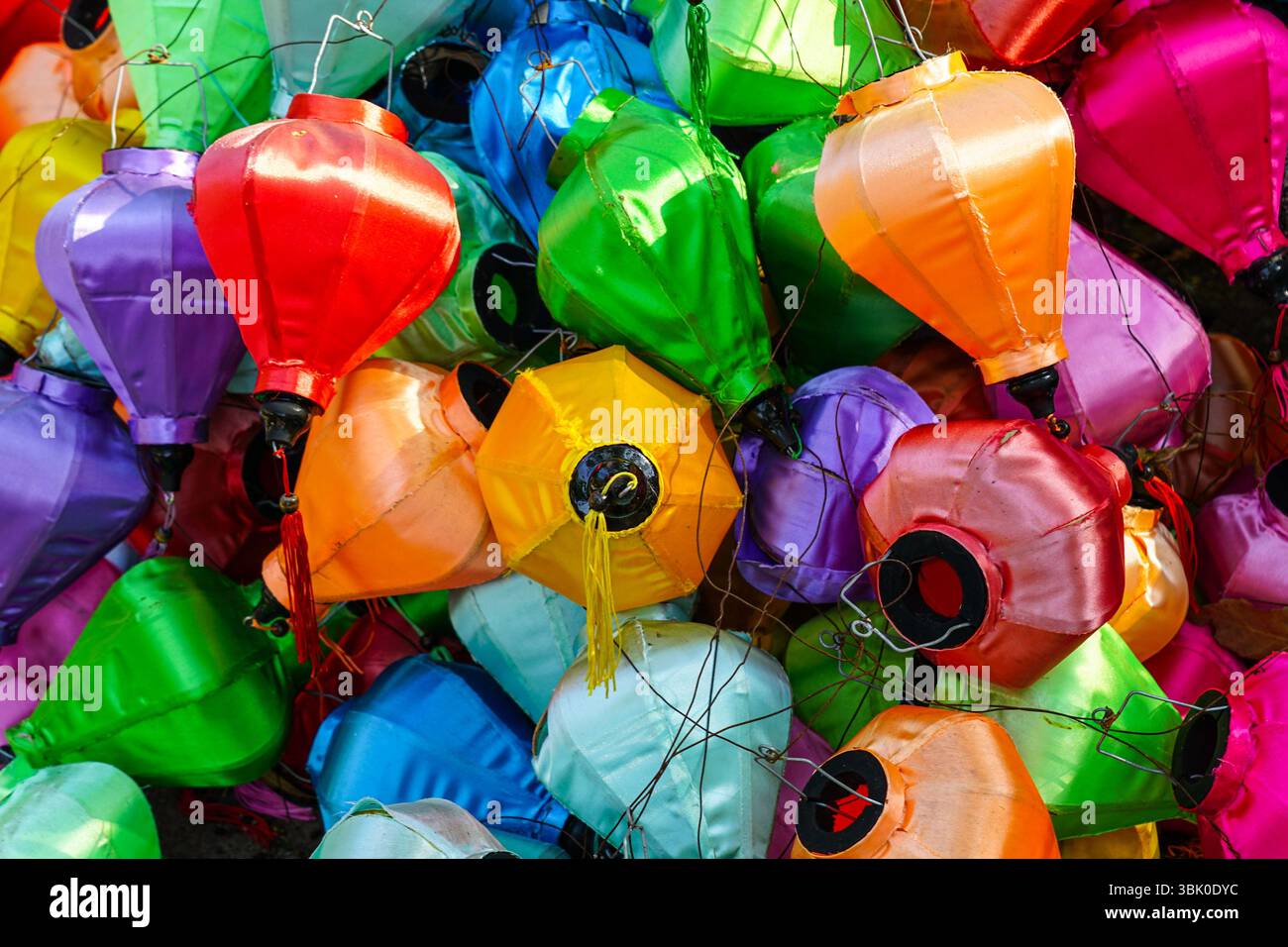 Lanterne di seta multicolore in pile, che mostrano sfumature festive utilizzate per feste tradizionali, Capodanno o mercati Foto Stock