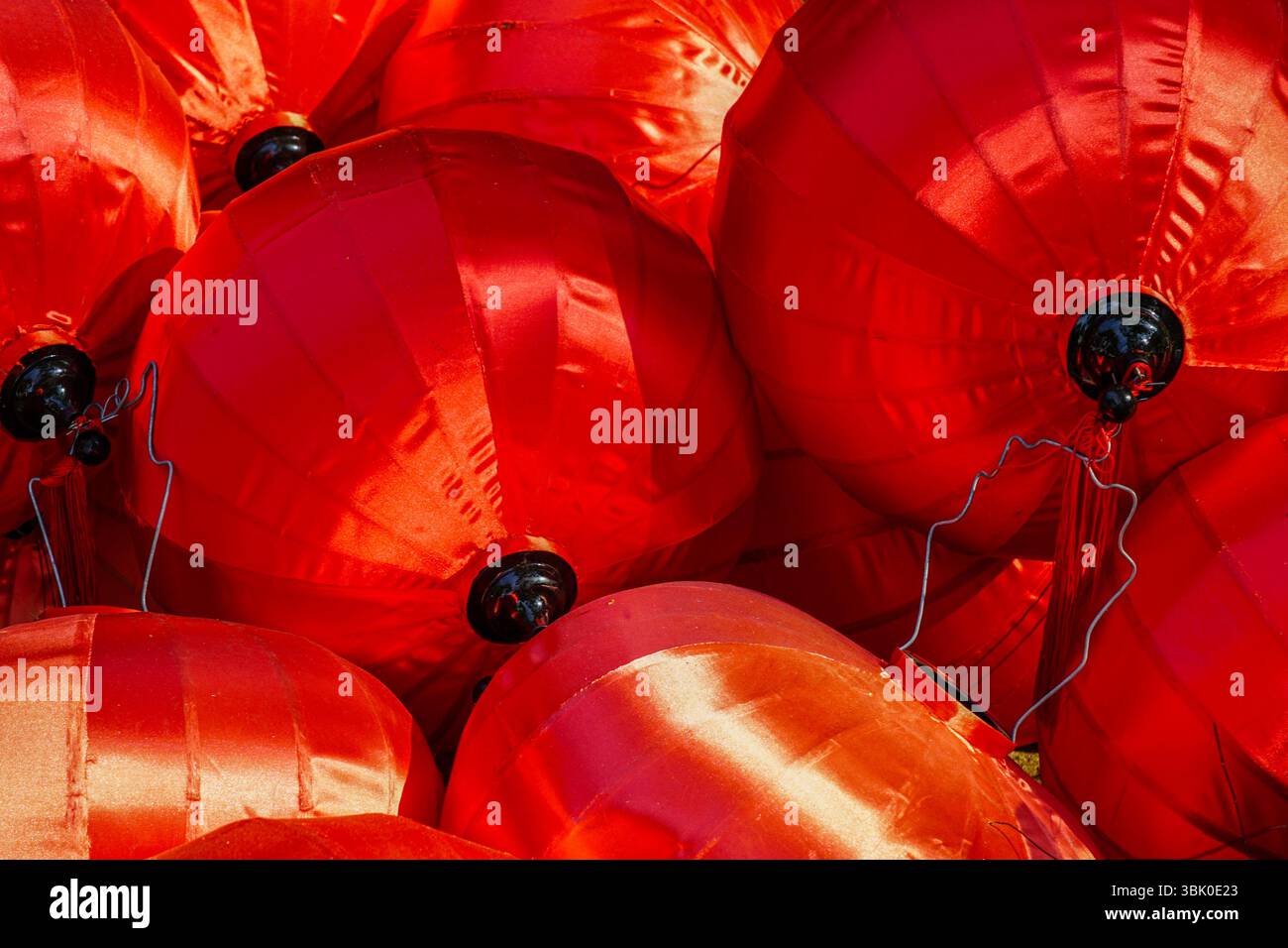 Lanterne di seta rosso brillante con dettagli neri e fili disposti in un gruppo festivo per festeggiare o decorare. Foto Stock