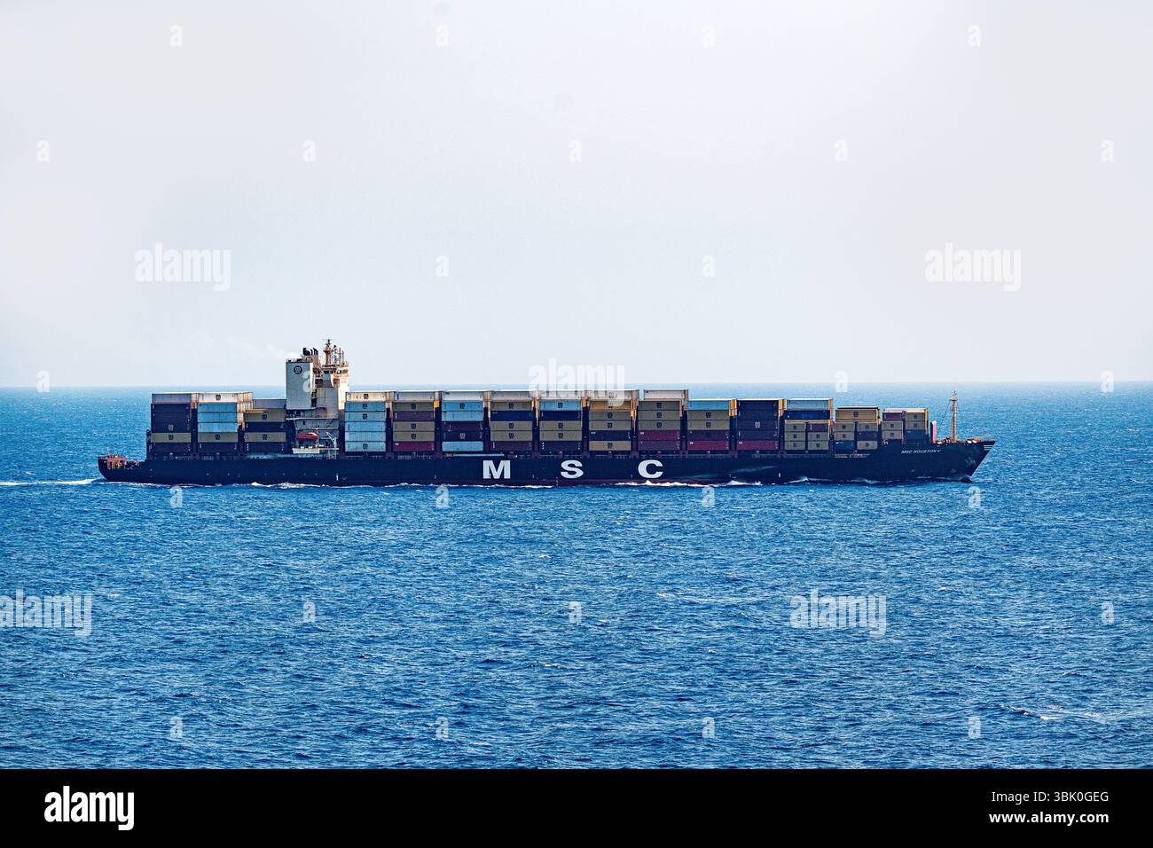 Mediterraneo, Europa - 11 giugno 2025: Una grande nave portacontainer della compagnia di navigazione MSC MSC Houston V trasporta numerosi container attraverso il mare aperto - un simbolo del commercio globale, dei trasporti e della logistica moderna in alto mare in tutta Europa verso il mondo. *** Ein Großes Containerschiff der Reederei MSC Houston V transportiert zahlreiche container über das offene Meer Symbol für globalen Handel, Transport und moderne Logistik auf hoher SEE über Europa in Die Welt. Foto Stock
