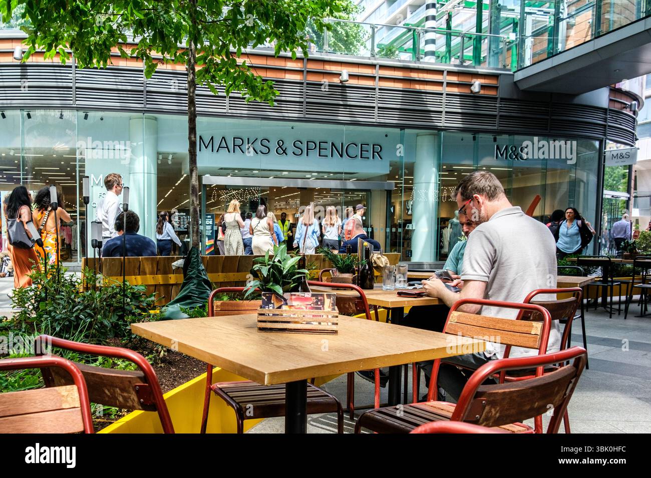 Victoria London UK, 17 giugno 2025, Anonymous Man Reading with A Marks and Spencer Store in the background Foto Stock