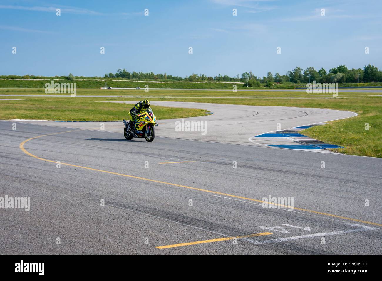 Motociclista che corre su una curva della pista Porsche Foto Stock