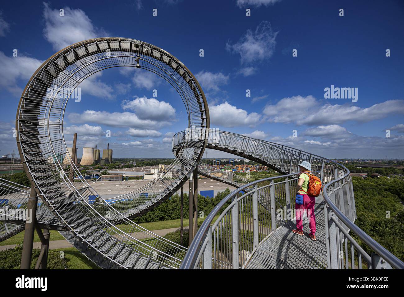 Una donna si erge su una scala che termina in un giro spettacolare, con lo skyline di Duisburg sullo sfondo, Tiger & Turtle, Duisburg, Nord Reno-W Foto Stock