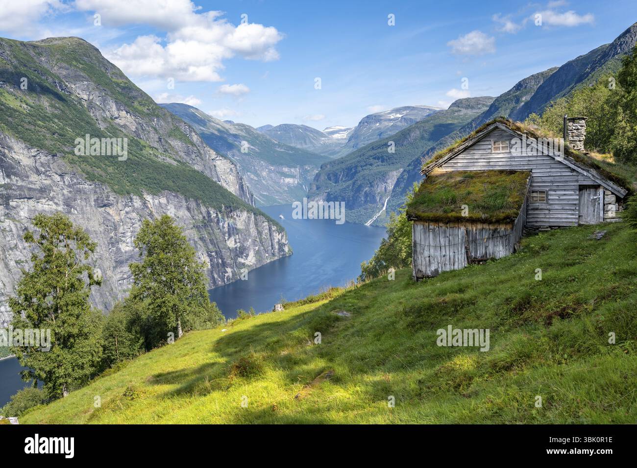 Blomberg Gard, storica fattoria di montagna con tetto in erba su una ripida montagna sopra il Geirangerfjord, vista dell'idilliaco paesaggio dei fiordi, vicino a Geirang Foto Stock