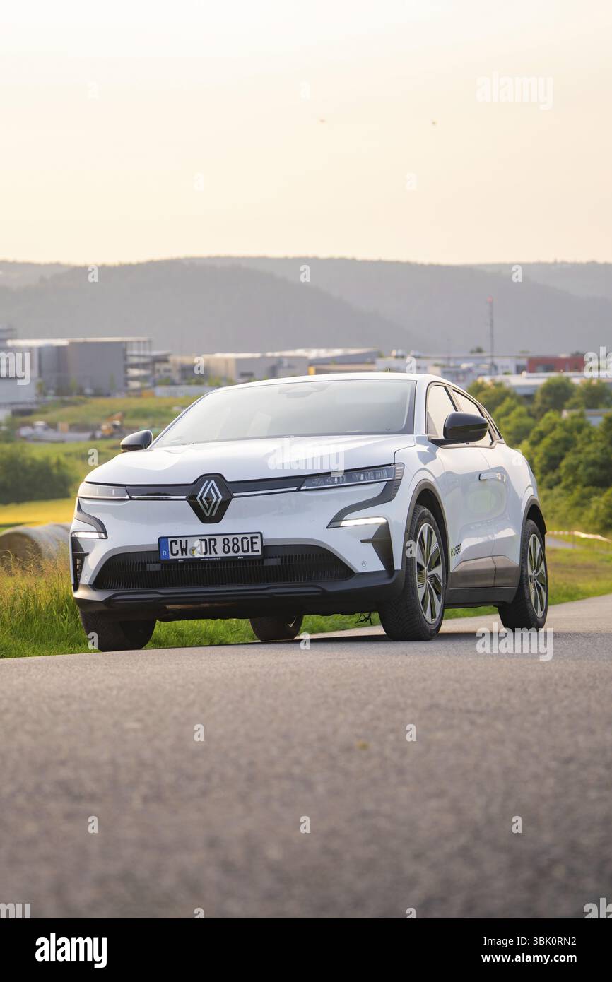 Auto che percorre una strada con vista su edifici moderni sullo sfondo, Renault Megane, Deer e- Carsharing, auto elettrica, Gechingen, Germania, Euro Foto Stock