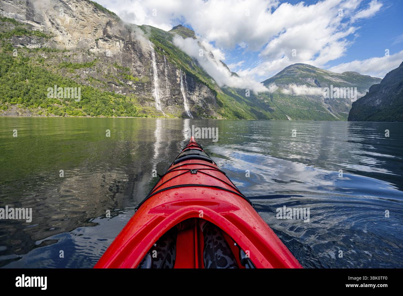 Gita in kayak sul Geirangerfjord con la cascata le sette Sorelle, punta di un kayak rosso nel fiordo, paesaggio suggestivo del fiordo con riflessi, per prima cosa Foto Stock