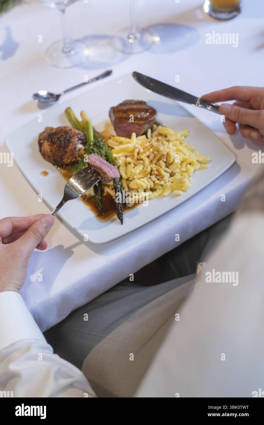 Un piatto di carne, asparagi e spaetzle su un tavolo bianco con posate, location per eventi e matrimoni Kloster Lorch, Lorch, Germania, Europa Foto Stock