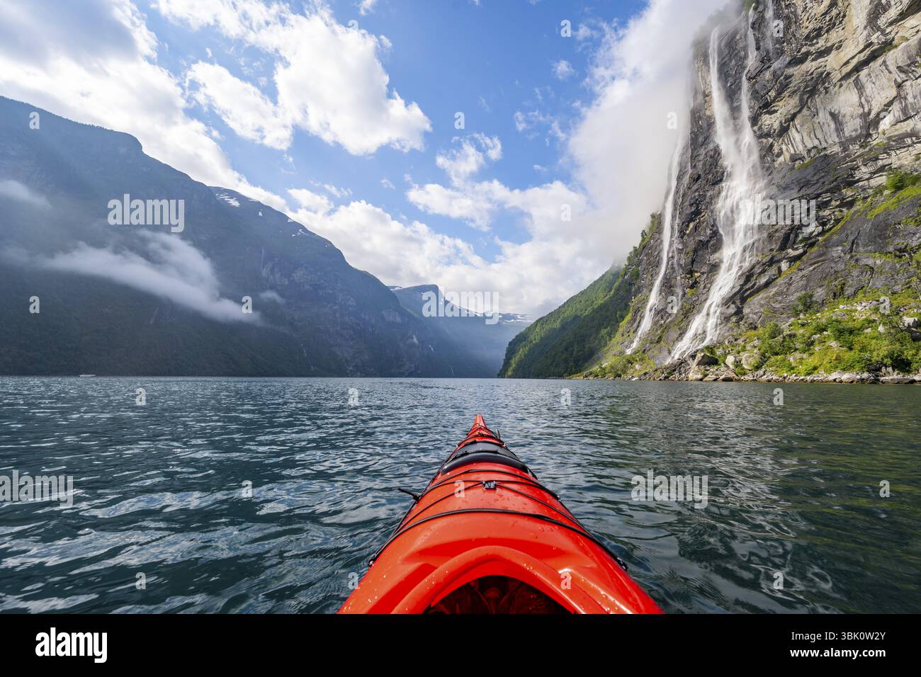 Gita in kayak sul Geirangerfjord presso la cascata The Seven Sisters, punta di un kayak rosso nel fiordo, suggestivo paesaggio del fiordo, vista in prima persona, Foto Stock