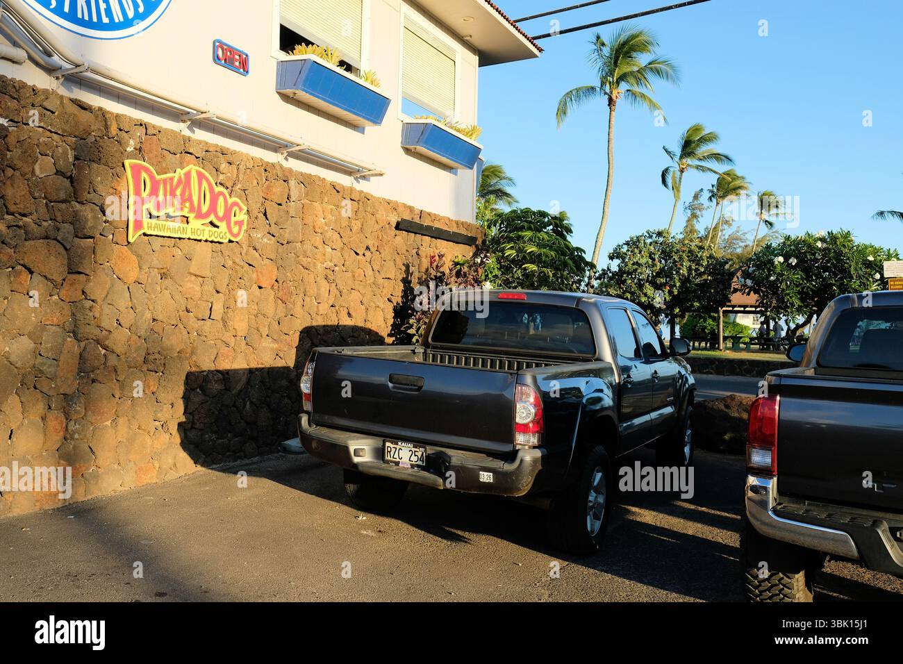Insegna a Puka Dog di fronte alla spiaggia di Poipu a Koloa, Kauai, Hawaii; popolare venditore di hot dog in stile hawaiano con un panino a forma di tubo. Foto Stock