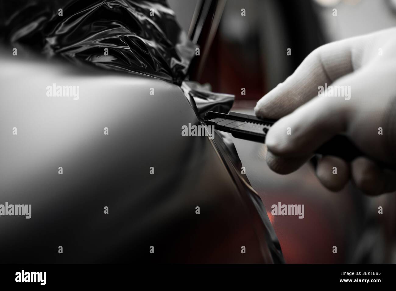 Rivestimento in vinile per auto a pannello intero. L'installazione di un involucro in vinile su larga scala trasforma l'esterno del veicolo con una pellicola nera opaca. Modifiche all'applicazione di avvolgimento per auto Foto Stock