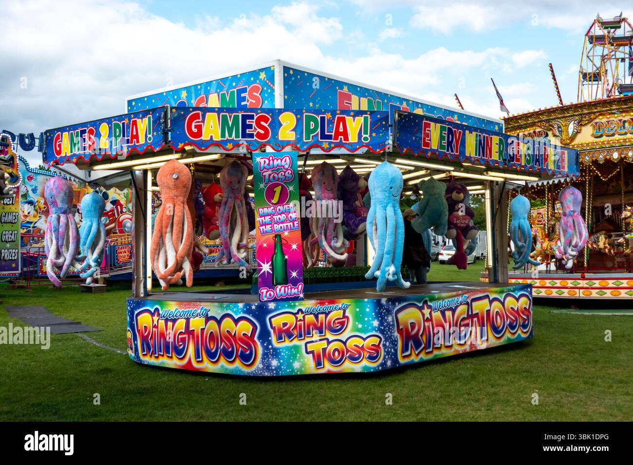 Una vivace partita di lancio ad anello in una fiera di Saffron Walden, Essex, Inghilterra. I premi includono peluche, che si aggiungono all'atmosfera festosa. Foto Stock