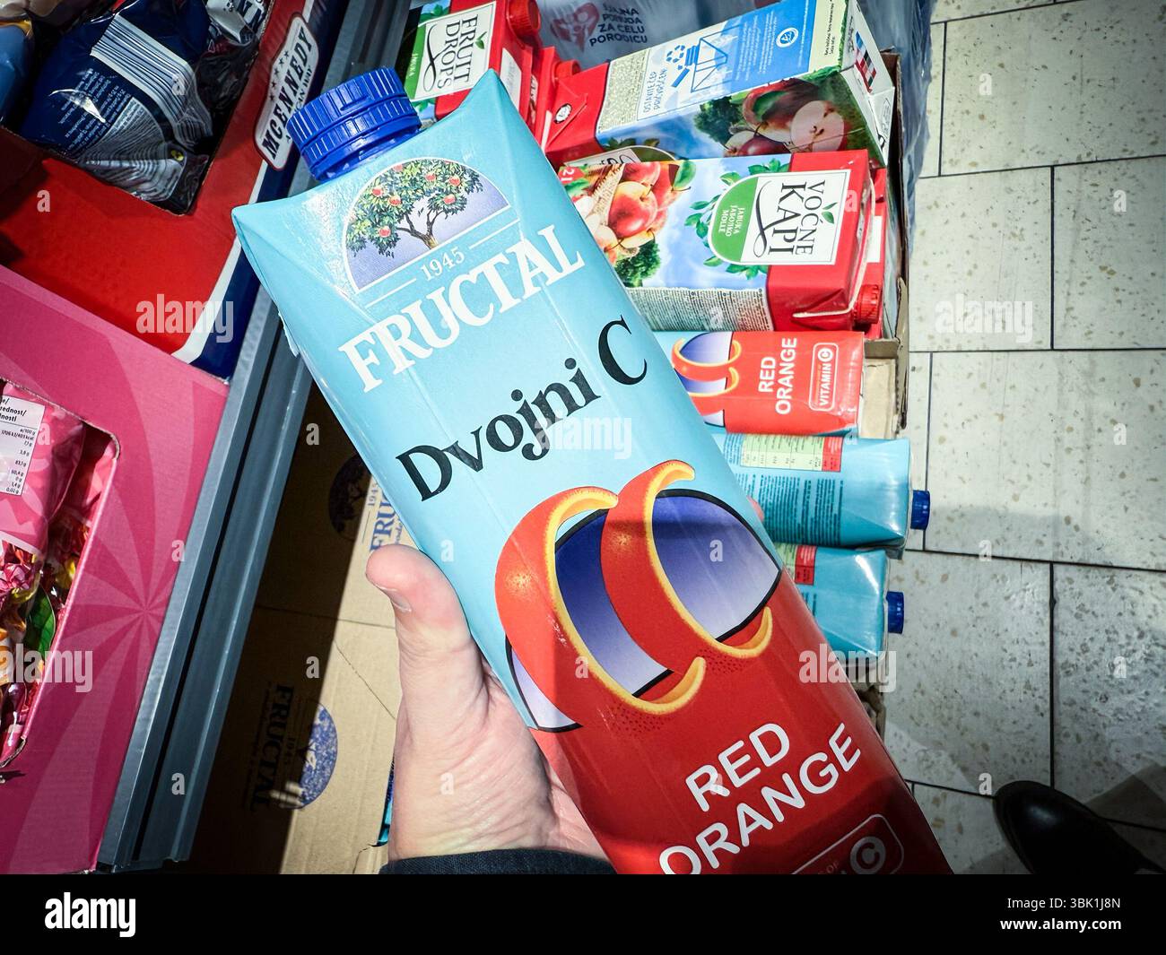 BELGRADO, SERBIA - 22 APRILE 2025: Primo piano di un cartone di succo d'arancia rosso Fructal Dvojni C tenuto in mano in un supermercato di Belgrado,. il fruttale è un po' sciocco Foto Stock