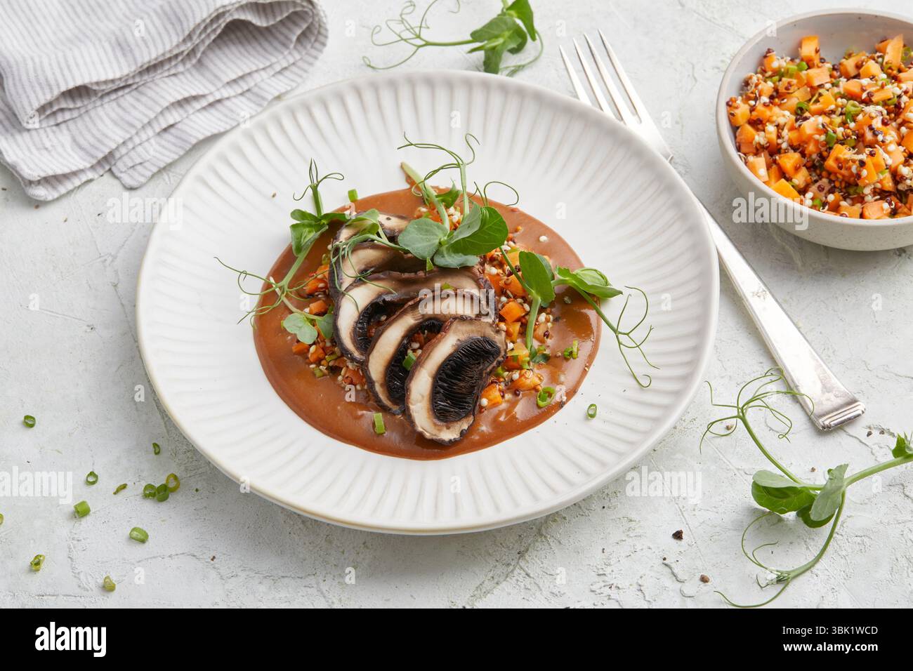 bistecca vegana di portobello e mandorle alla griglia con ricca salsa marrone, servita su un piatto bianco, un piatto abbondante a base di piante, perfetto per pranzo o cena. Foto Stock