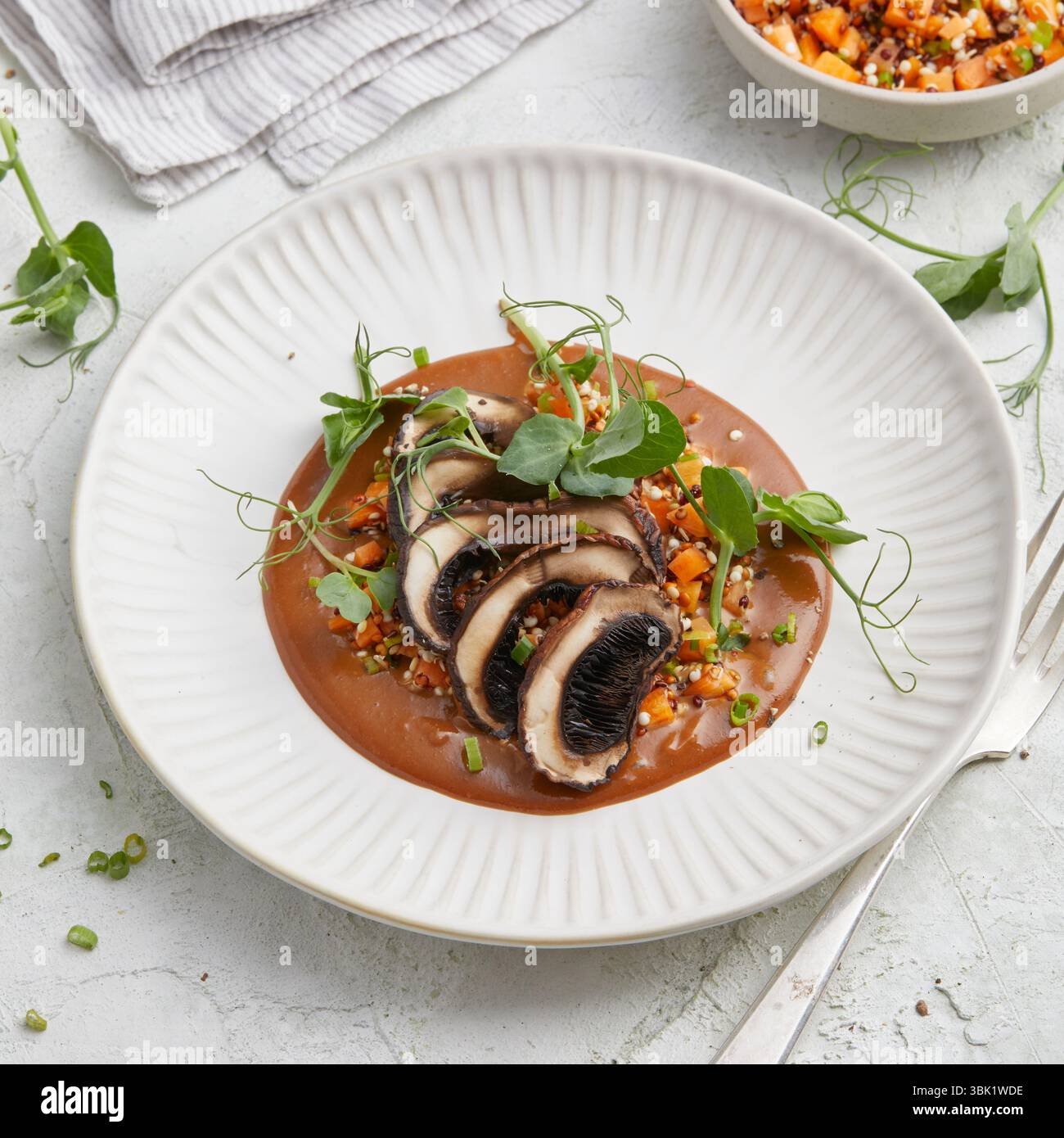 bistecca vegana di portobello e mandorle alla griglia con ricca salsa marrone, servita su un piatto bianco, un piatto abbondante a base di piante, perfetto per pranzo o cena. Foto Stock