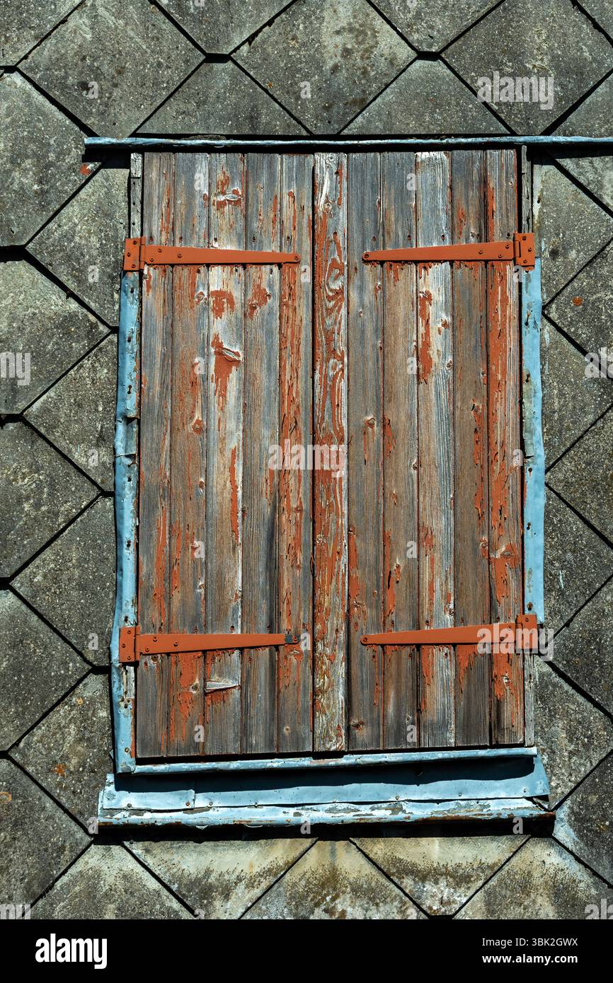 Persiane chiuse in legno con vernice che si stacca contro un edificio vecchio, Auvergne, Francia Foto Stock
