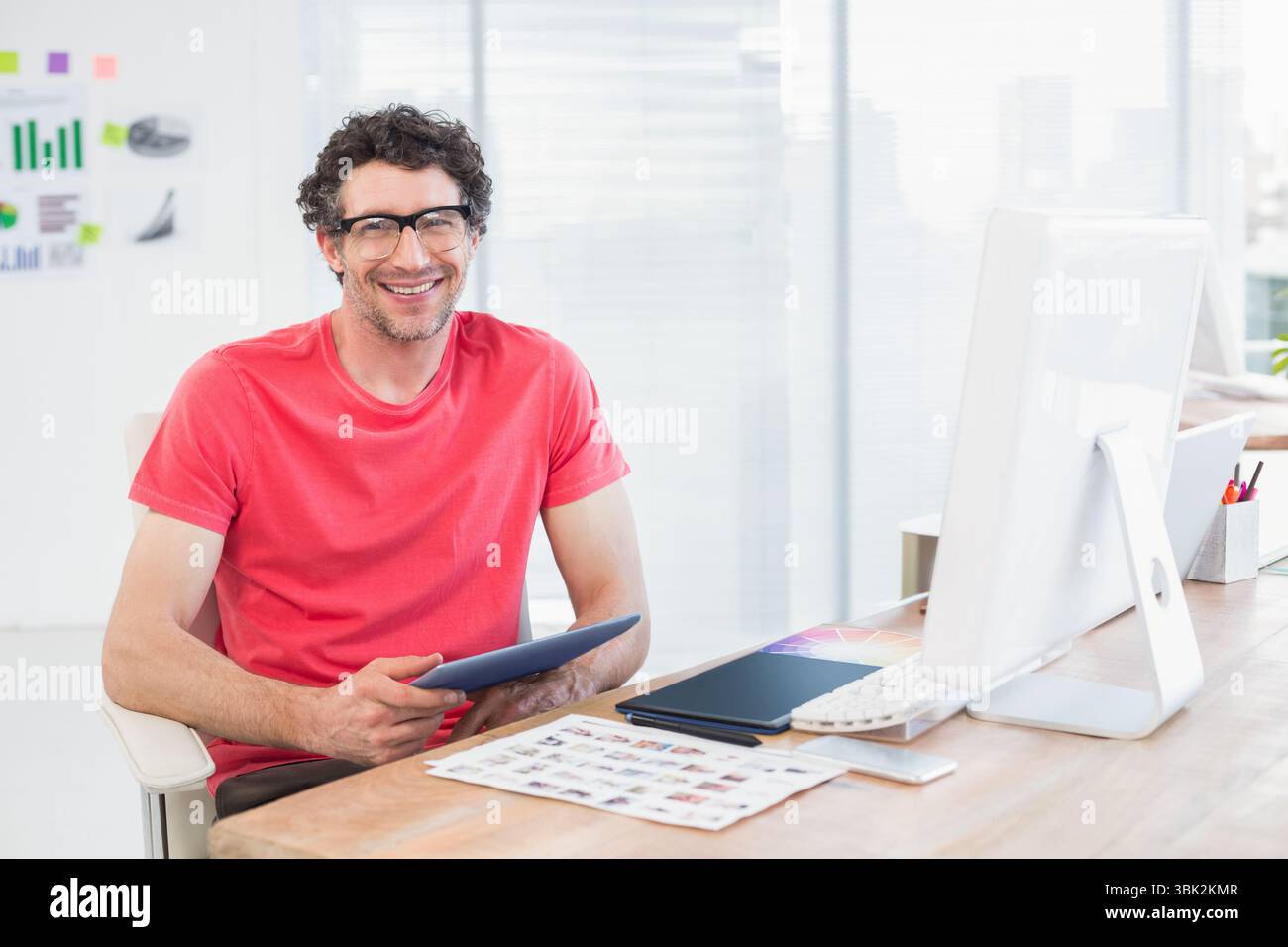 Il tablet viene tenuto sopra la scrivania con un campionario a colori e uno smartphone in ufficio vicino allo skyline Foto Stock