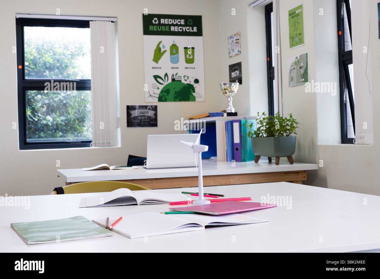 Classe incentrata sulla sostenibilità con il modello di turbine eoliche e i notebook aperti, a scuola Foto Stock