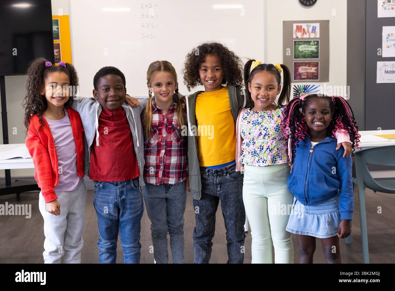Un gruppo di bambini sorridenti in piedi insieme in classe, godendo della scuola Foto Stock