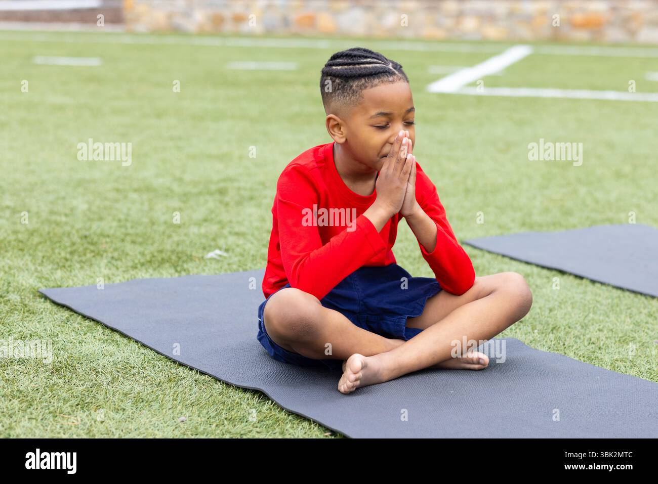 Bambini che meditano sul tappetino yoga all'aperto, esercitano consapevolezza e relax Foto Stock