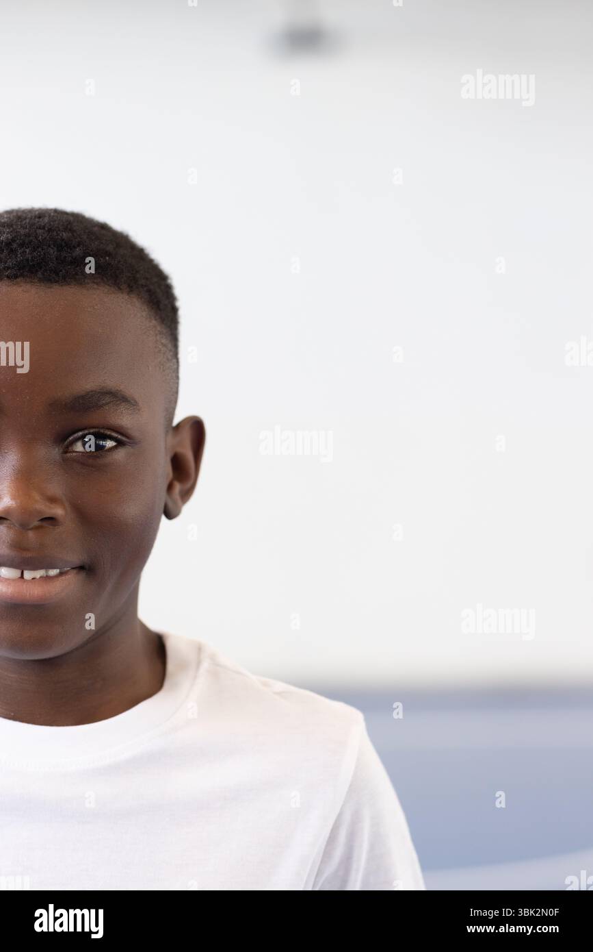 Sorridente ragazzo afroamericano in camicia bianca che si gode la giornata scolastica in classe, copia spazio Foto Stock