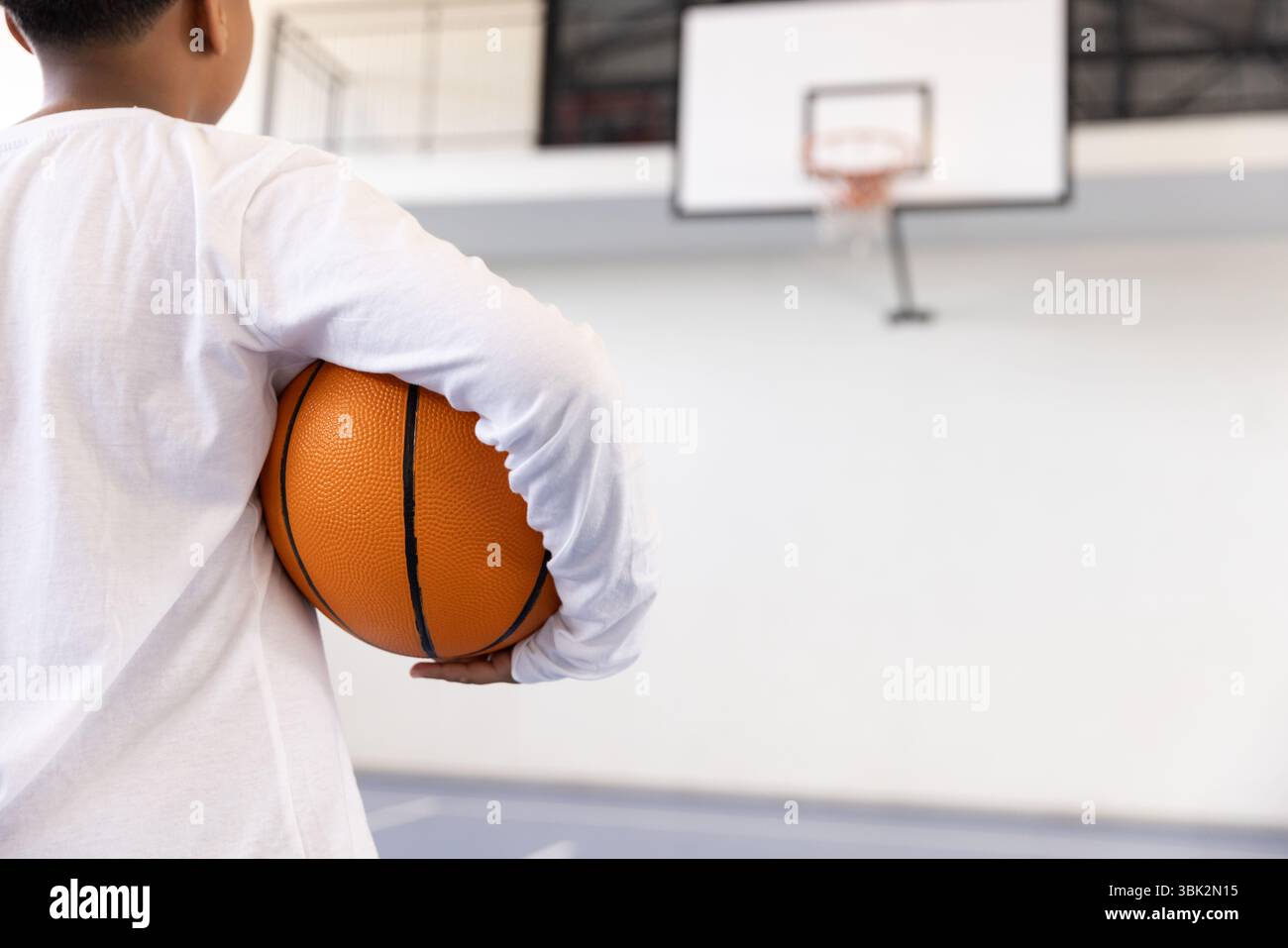 Ragazzo che tiene il basket in palestra, si prepara per una sessione di allenamento a scuola Foto Stock