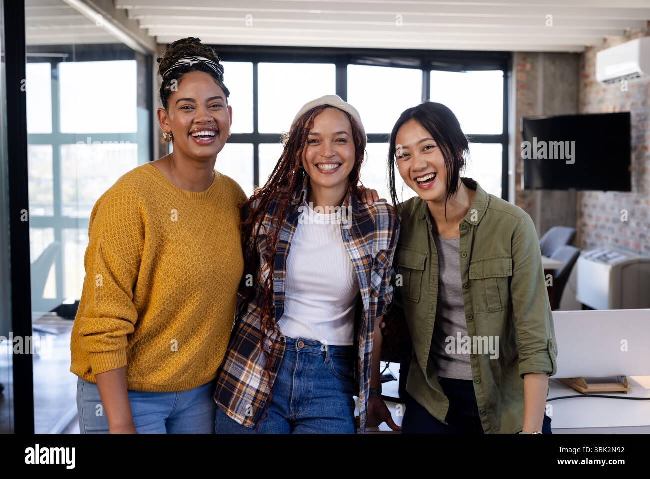 Donne diverse in ufficio sorridono con fiducia, abbracciano il lavoro di squadra e l'innovazione Foto Stock