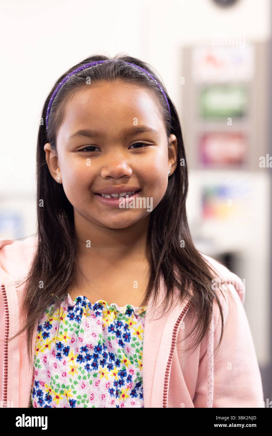 Ragazza sorridente in abito colorato che si gode la giornata scolastica in classe Foto Stock Ragazza sorridente in abito colorato che si gode la giornata scolastica in classe Foto Stock