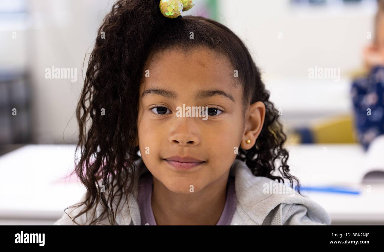 Ragazza sorridente in classe che guarda la fotocamera, si sente sicura di sé e concentrata, a scuola Foto Stock