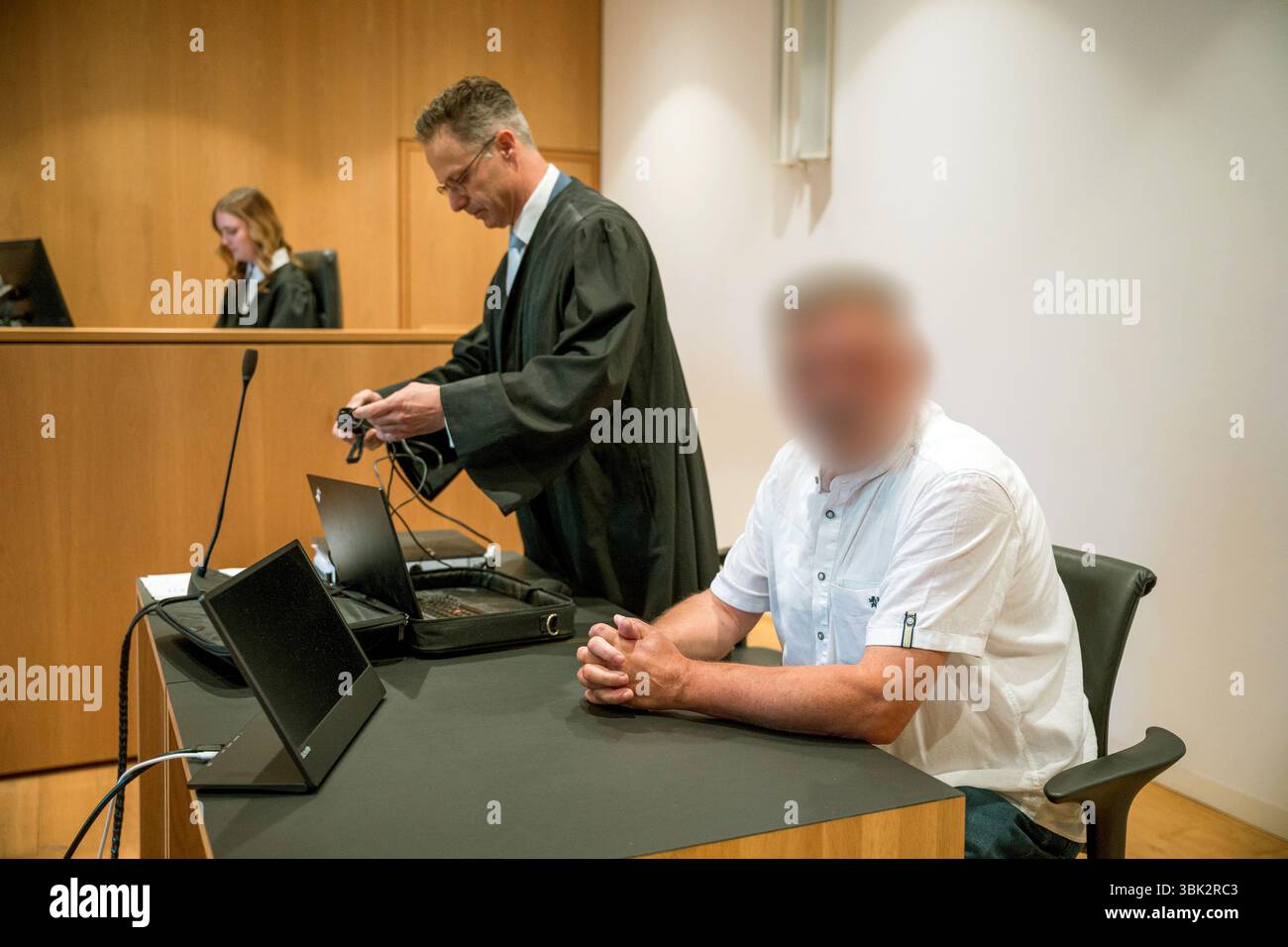 18 giugno 2025, Baviera, Haßfurt: L'imputato (r) si siede in tribunale all'inizio del processo per aver usato segni di organizzazioni incostituzionali e terroristiche e per istigazione al popolo. Il suo avvocato difensore Marcus Pretzell (M) prepara la sua postazione di lavoro. Nella primavera del 2024, l'accusato avrebbe caricato un file immagine su X con una foto ritratto dell'allora ministro federale dell'economia Habeck (Verdi) e le parole "Schwachkopf PROFESSIONAL". Ciò ha portato a un raid nella casa del sospetto nel distretto di Haßberge nella bassa Franconia. Foto: Daniel Vogl/dpa - ATTENZIONE: L'imputato o gli imputati hanno/hanno Foto Stock