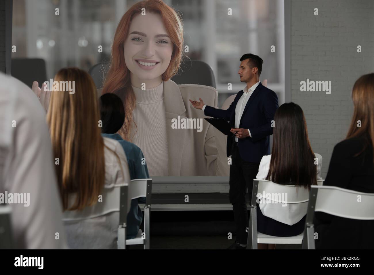 Gruppo di persone che partecipano a una conferenza aziendale al chiuso. Altoparlante sullo schermo di proiezione Foto Stock