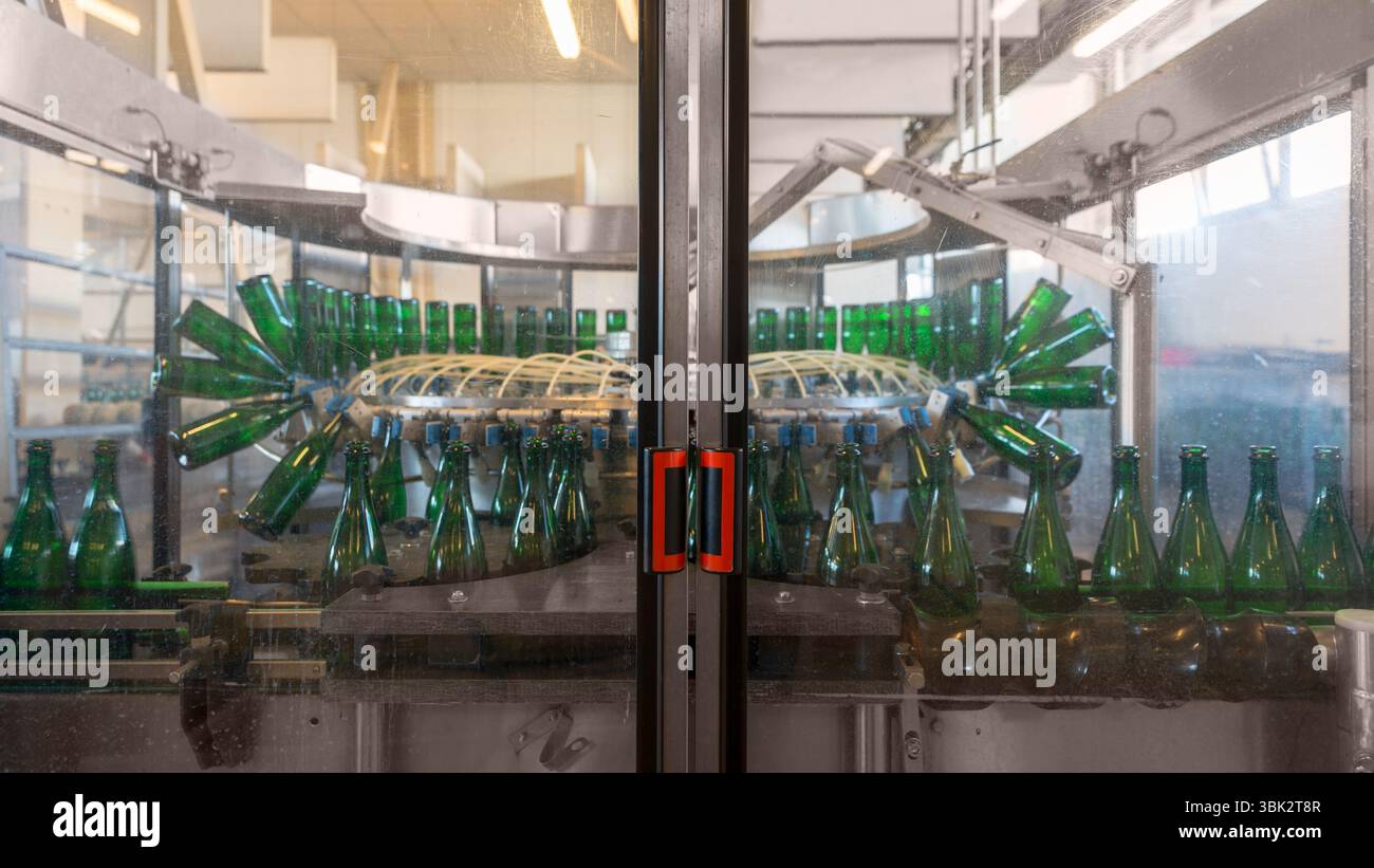 Imbottigliatrice con molte bottiglie in fabbrica Foto Stock