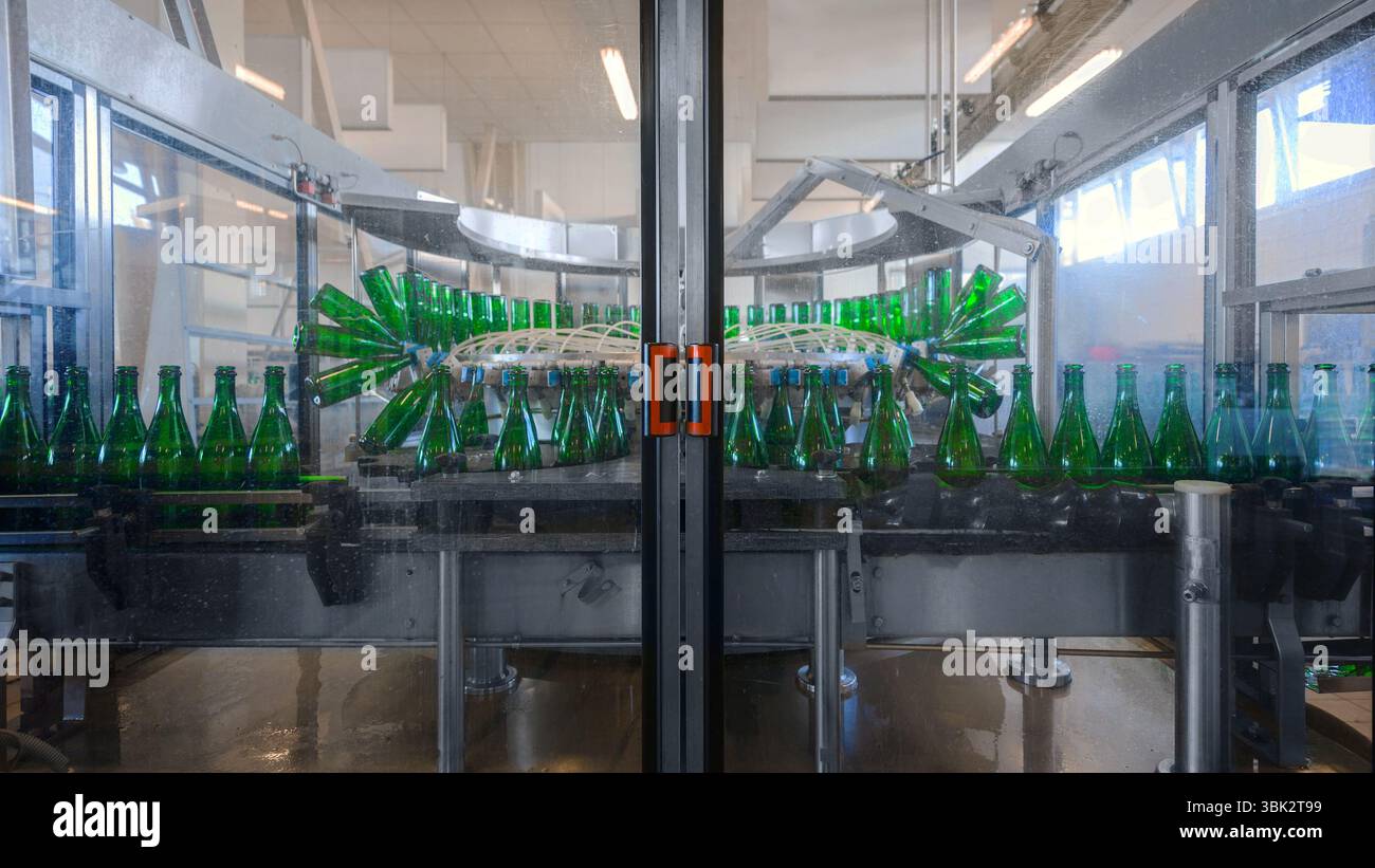 Imbottigliatrice con molte bottiglie in fabbrica Foto Stock