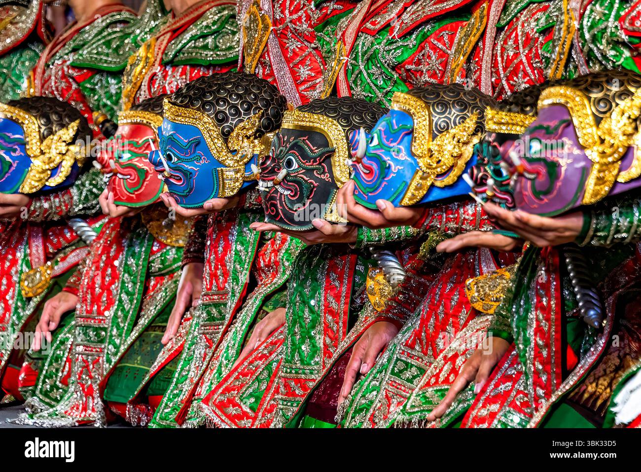 Una linea di artisti in vivaci ed elaborati costumi tradizionali contiene maschere stilizzate, raffiguranti personaggi demoniaci della storia di Ramayana. Foto Stock