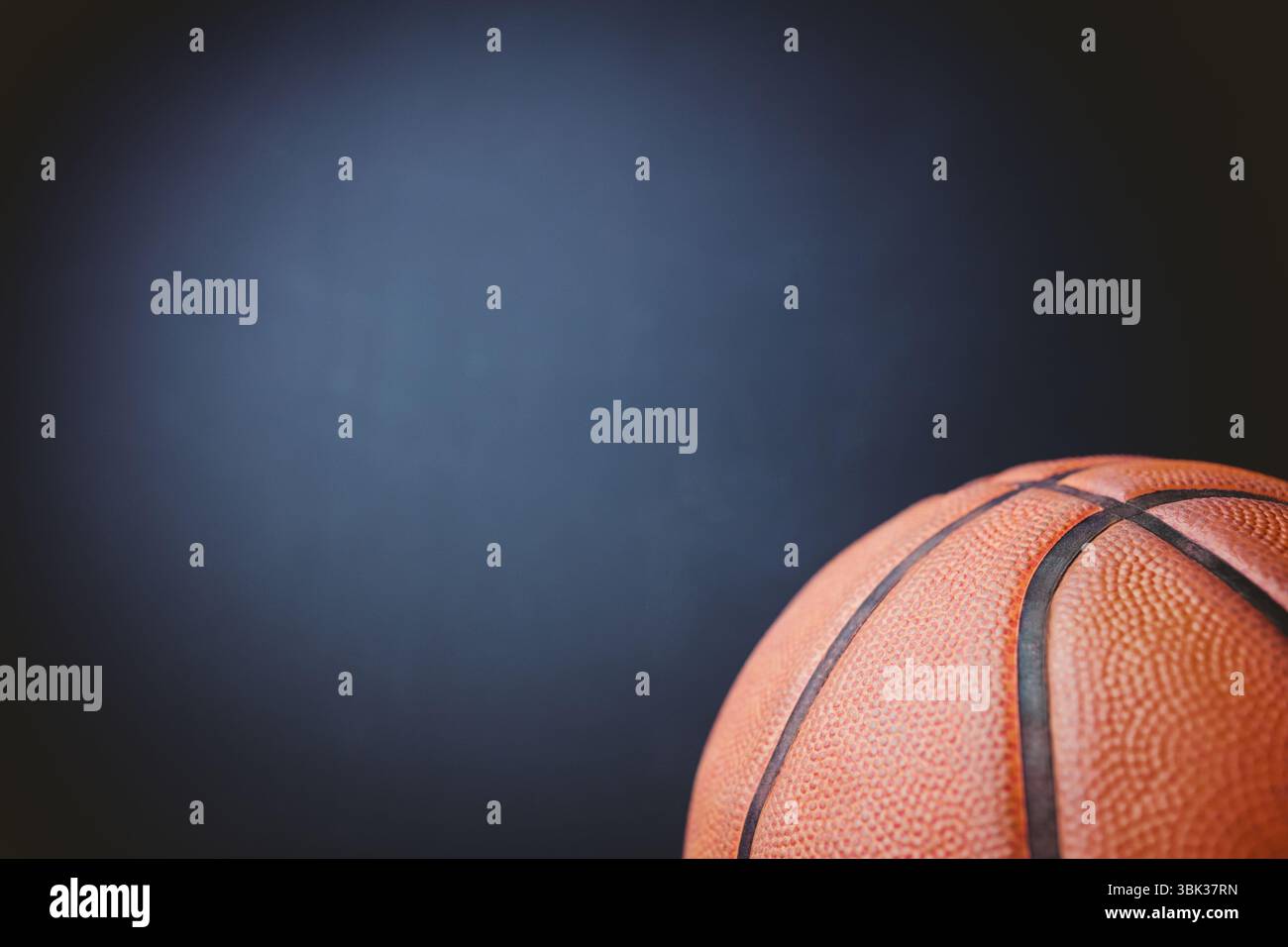 La pallacanestro arancione si trova sul bordo destro con rendering 3D con sfondo testurizzato sfumato scuro Foto Stock
