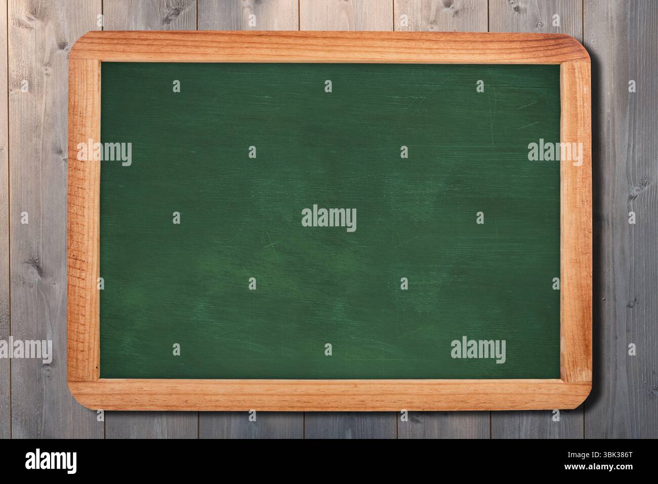 Il design piatto mostra una lavagna verde con telaio in legno chiaro su parete con pannelli in legno grigio, spazio di copia Foto Stock