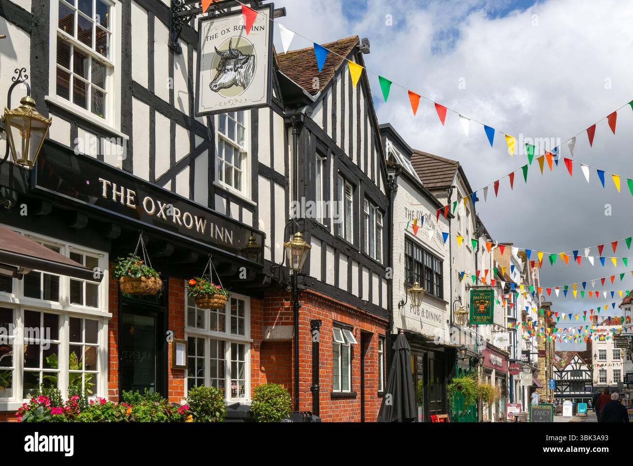 Bandiere che decorano gli edifici della strada storica, The Ox Row Inn and Shops, Butcher Row, Salisbury, Wiltshire, Inghilterra, REGNO UNITO Foto Stock