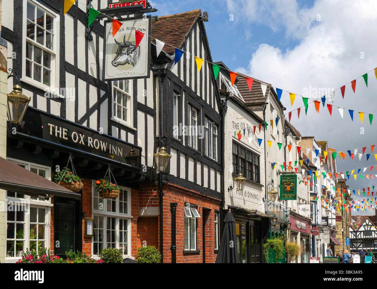 Bandiere che decorano gli edifici della strada storica, The Ox Row Inn and Shops, Butcher Row, Salisbury, Wiltshire, Inghilterra, REGNO UNITO Foto Stock