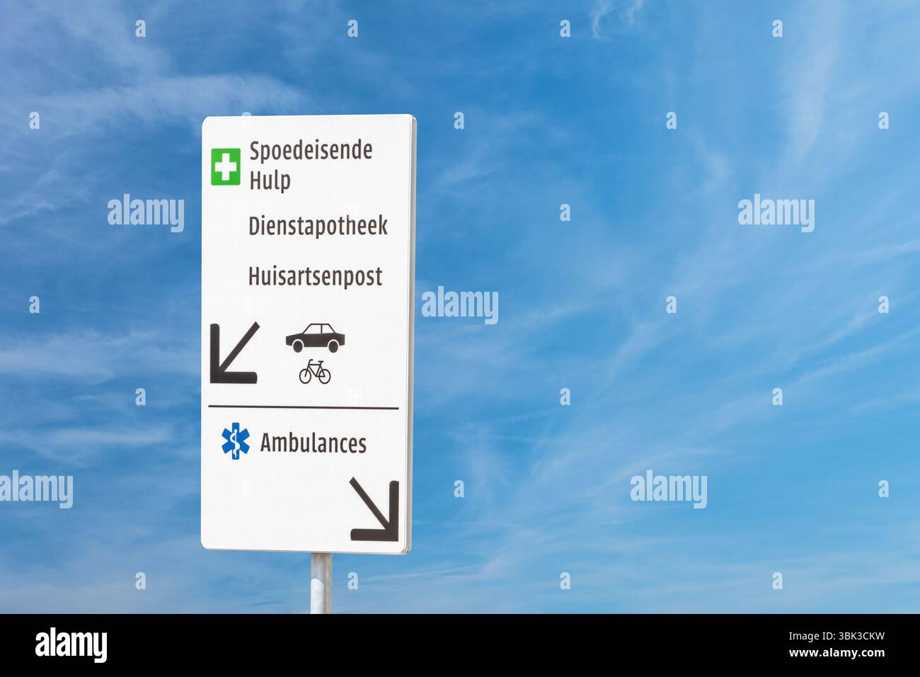 Cartello con il testo olandese per la cura Emercengy, la farmacia di servizio, il medico di famiglia medico di famiglia medico e l'ambulanza di fronte a un cielo blu Foto Stock