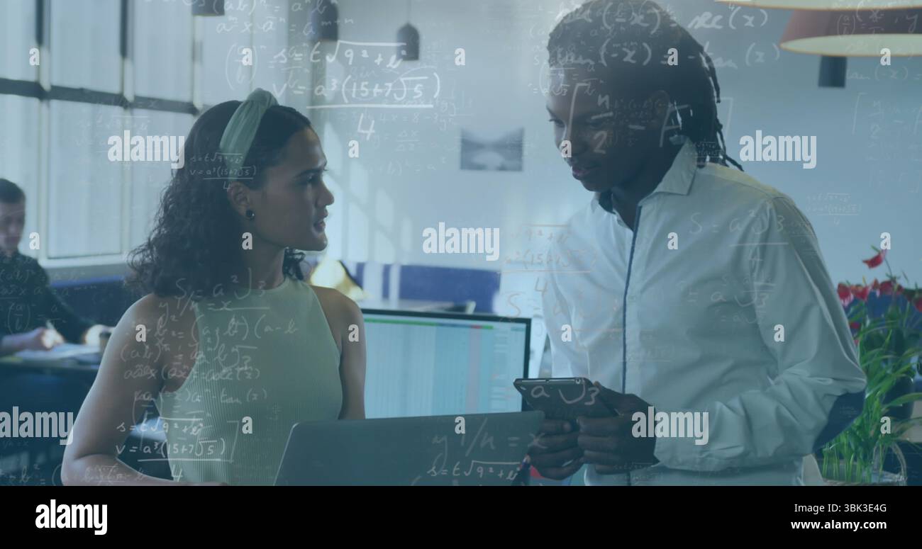 Donna con il top verde e collega di sesso maschile che parla di contenuti digitali in ufficio, con notebook e tablet Foto Stock