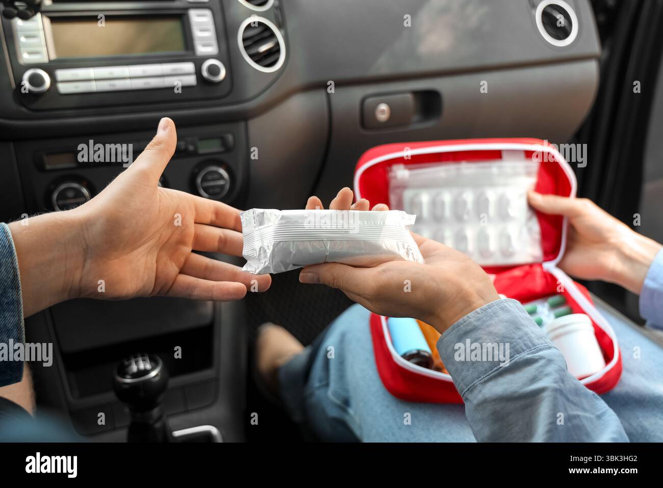 Donna che passa bende dal kit di pronto soccorso al conducente maschio in auto Foto Stock