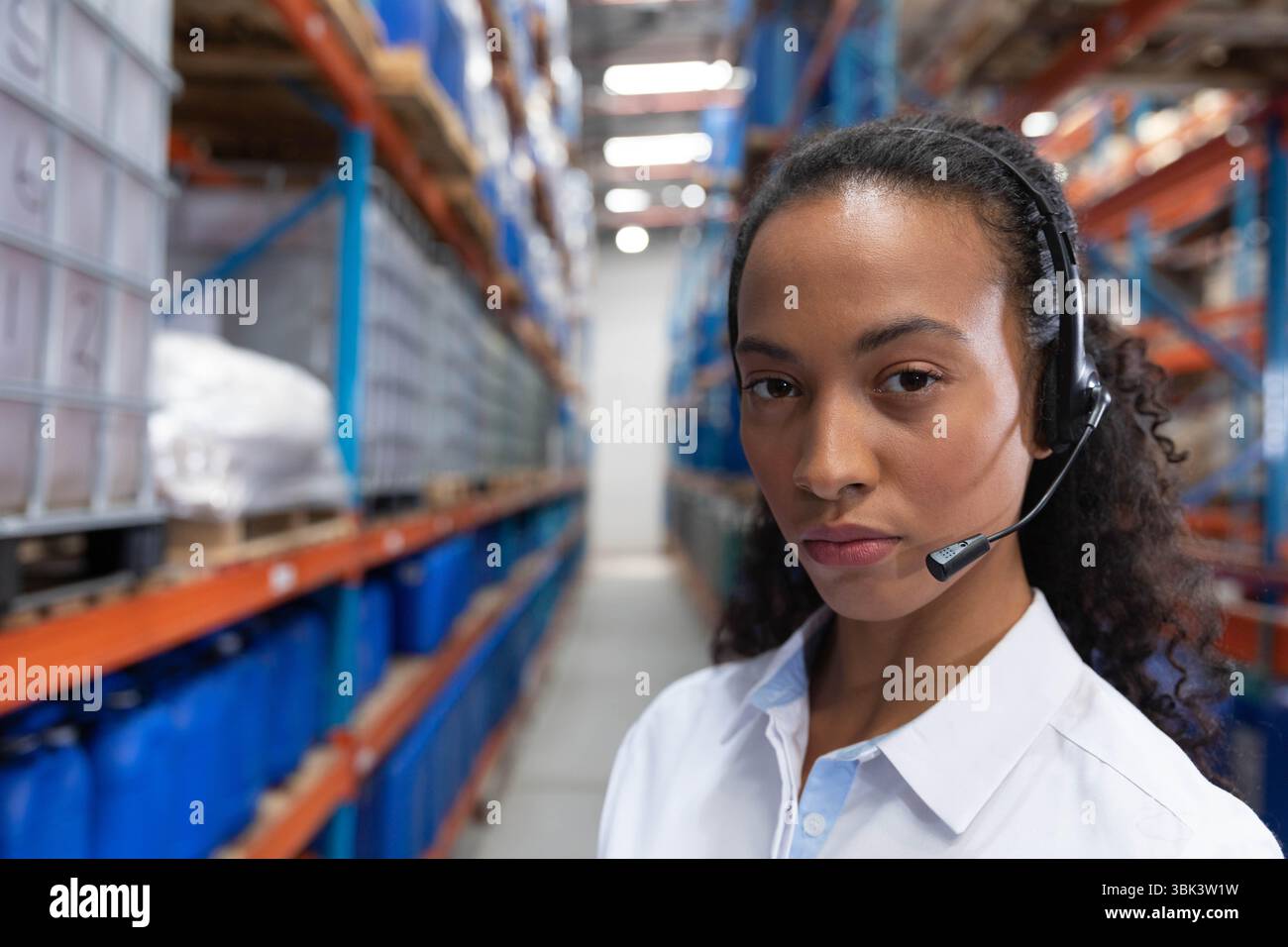 Rack per magazzini con contenitori blu, contenitori bianchi illuminati da luci dall'alto Foto Stock
