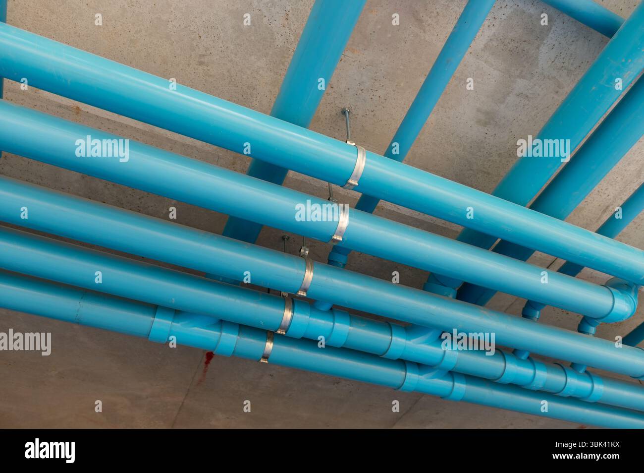 Impianto idraulico organizzato con staffe metalliche che fissano i tubi a un soffitto in calcestruzzo Foto Stock